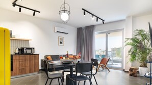 Uma sala de jantar moderna com uma mesa redonda, cadeiras e vista para a cidade através de grandes janelas.