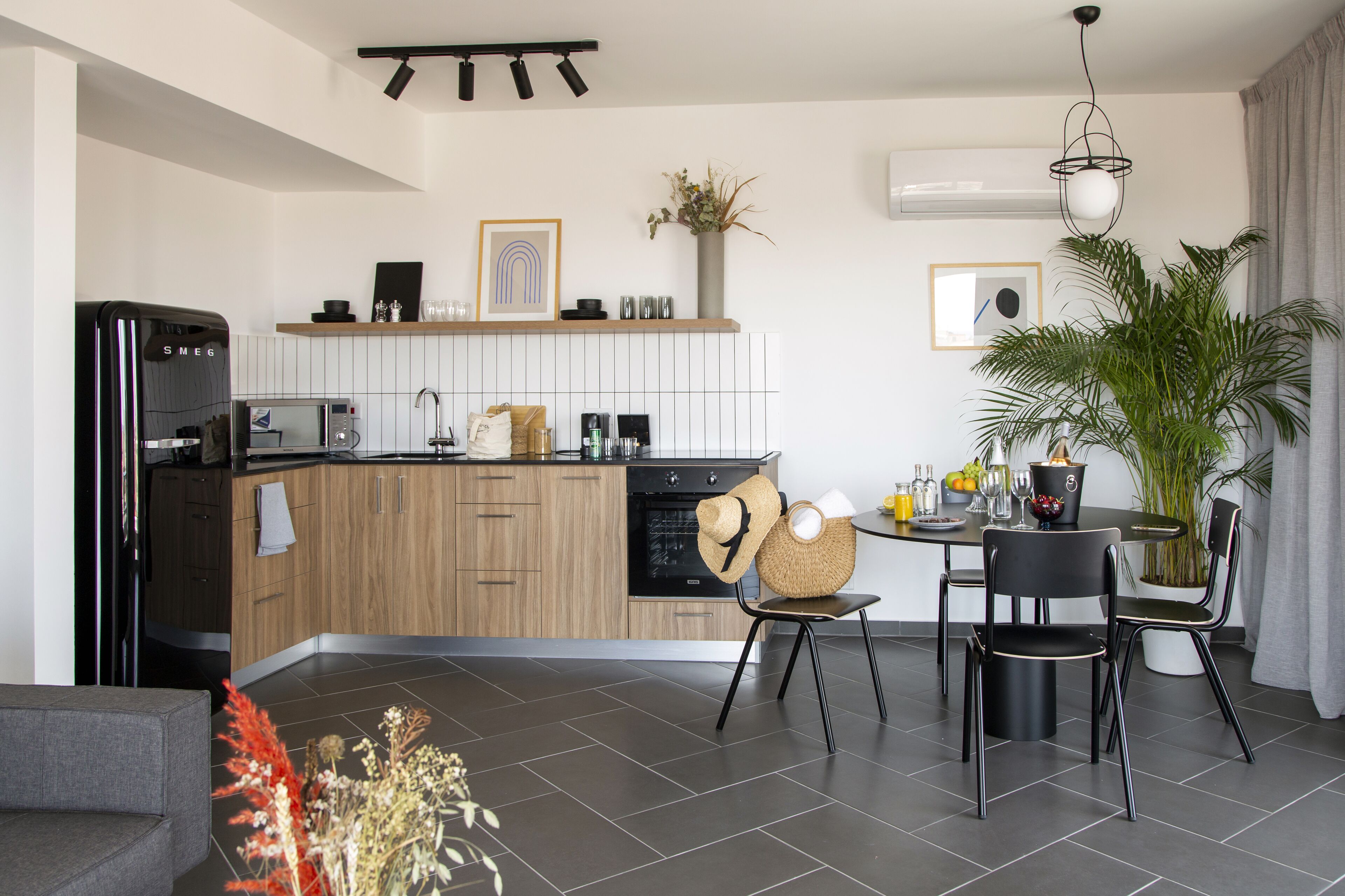 A modern kitchen with wooden cabinets, a built-in oven, and a dining area with a round table and chairs.