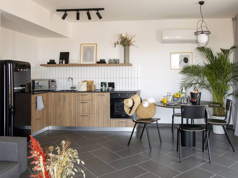 A modern kitchen with wooden cabinets, a built-in oven, and a dining area with a round table and chairs.