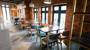 Een modern restaurant met bakstenen muren, grote ramen en verschillende zithoeken, waaronder tafels en stoelen.