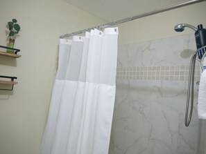 Een bad/douchecombinatie, een haardroger, handdoeken, zeep