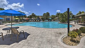 A swimming pool with lounge chairs and umbrellas, surrounded by palm trees and a clear sky. - Bright & Airy Fort Myers Home w/ Pool Access! (Fort Myers)