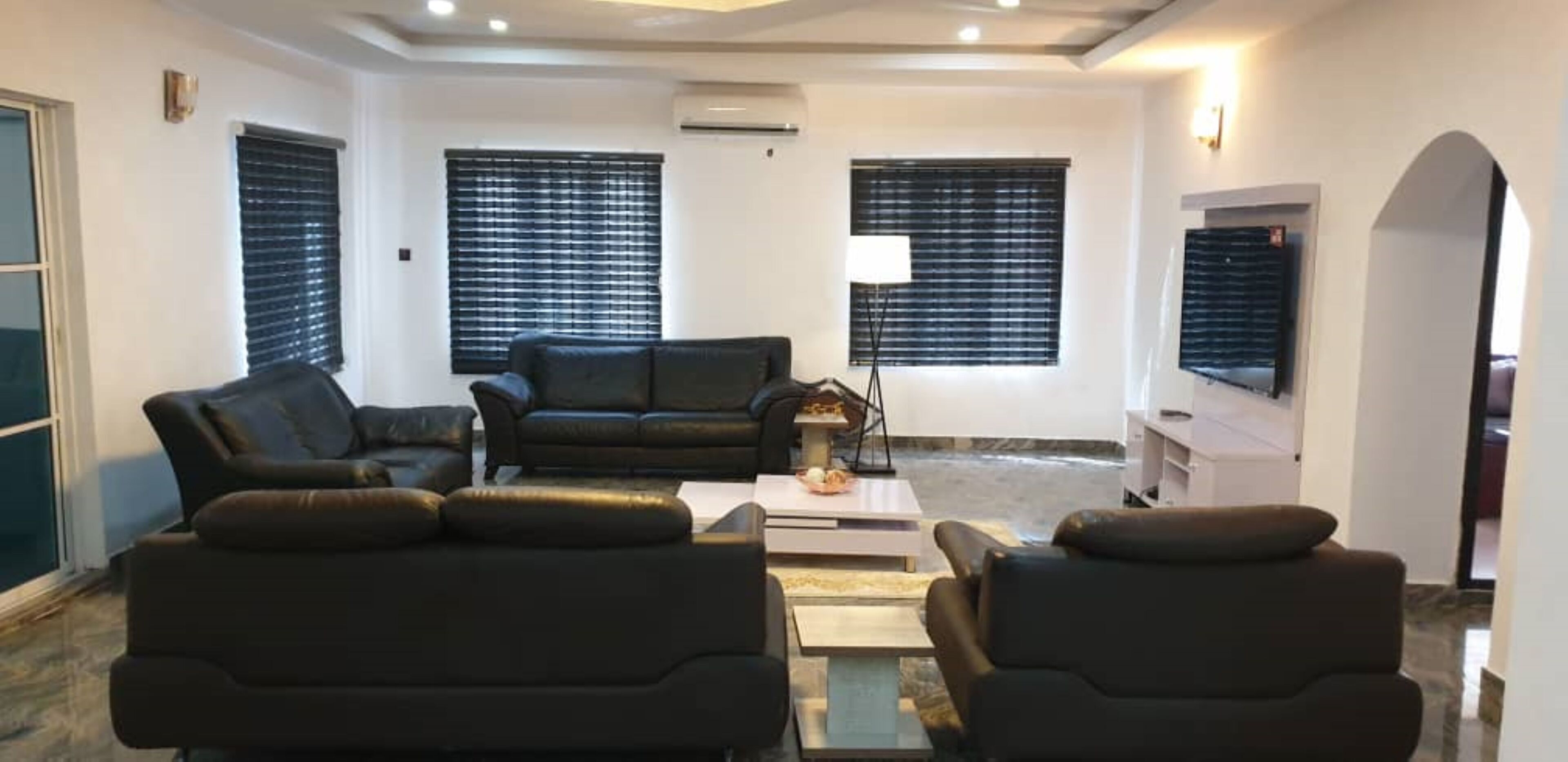 A modern living room with a sofa set, a coffee table, and a TV mounted on the wall.