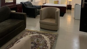 Una habitación de hotel moderna con una cama grande, dos sillones, un sofá, un escritorio y un espejo.