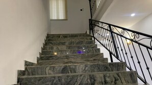 Una escalera de mármol con barandilla de metal negro que conduce a un piso superior.