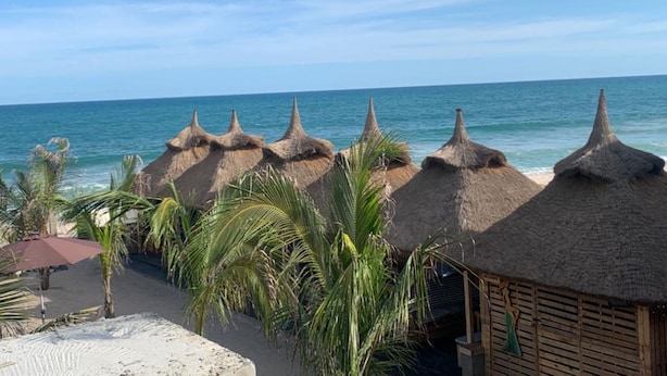 Una playa con cabañas de techo de paja y palmeras.