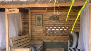 Una cabaña de madera con techo de paja, un banco, una mesita y un letrero que dice "PHIPP'S".