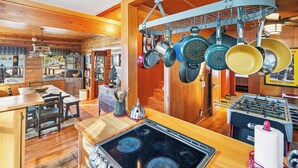 A kitchen with wooden cabinets, a stove, and hanging pots.