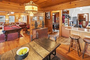 Un intérieur de chalet chaleureux et accueillant, avec une table de billard, un coin bar et un espace repas.