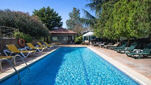 En swimmingpool med liggestole og en pavillon.