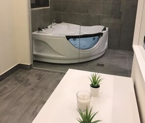 A modern bathroom with a large curved bathtub, a white vanity, and a potted plant. - Havana Villa-Luxurious stay in Dead Sea\Al-Ghour (Juwafat al-Kafrayn)