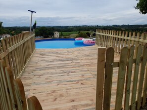 A wooden deck leading to a swimming pool with inflatable rings.