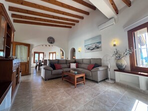 A spacious living room with a large sectional sofa, a coffee table, and a dining area in the background.