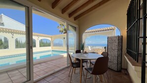 A patio area with a pool, a table with chairs, and a view of a building with arches. - T-0121, Canarios, Fantastic villa with panoramic sea views (Denia)