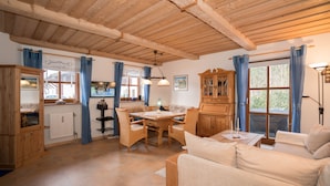 Una habitación acogedora con techo de madera, una mesa de comedor con sillas, un sofá y un armario.