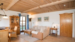 Una sala de estar acogedora con techo de madera, un sofá, una mesa de comedor con sillas, un aparador y una puerta.