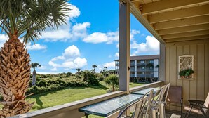 A balcony with a view of a grassy area and a building in the background. - Private balcony overlooking the beach! (Tybee Island)