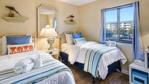 A hotel room with two beds, a large mirror, a window with a view of the outside, and a small table with a lamp. - Private balcony overlooking the beach! (Tybee Island)