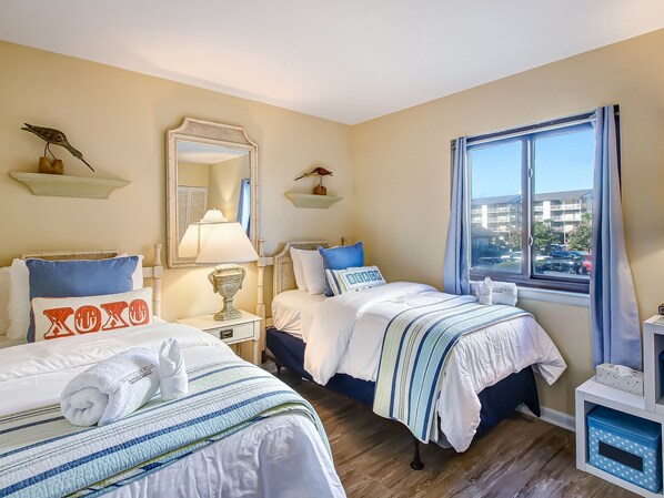 A hotel room with two beds, a large mirror, a window with a view of the outside, and a small table with a lamp. - Private balcony overlooking the beach! (Tybee Island)