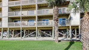 Un hotel de varios pisos con balcones, un estacionamiento y palmeras.