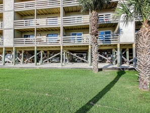 A multi-story hotel with balconies, a parking area, and palm trees. - Private balcony overlooking the beach! (Tybee Island)