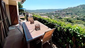A terrace with a table and chairs, overlooking a scenic view of a village and hills. - AMAZING VILLA with, chimney, heating, private swimming pool & great views. (Calonge)