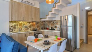 Una cocina moderna con comedor, una escalera y un refrigerador.
