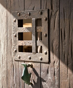 A rustic metal door with a square window and a green doorbell. - Villa Petrolefko (Mykonos)