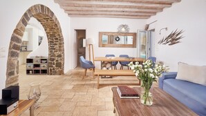 Un espacio habitable amplio con un arco de piedra, techo de madera, mesa de comedor con sillas, un sofá y una mesa de centro con un jarrón de flores.