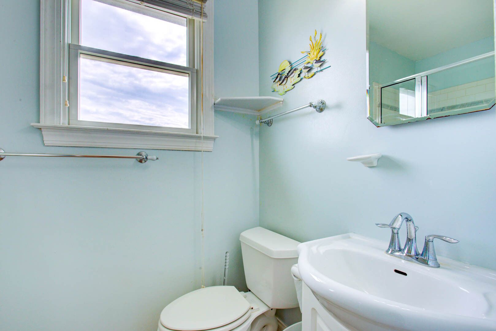 A bathroom with a toilet, sink, and window.