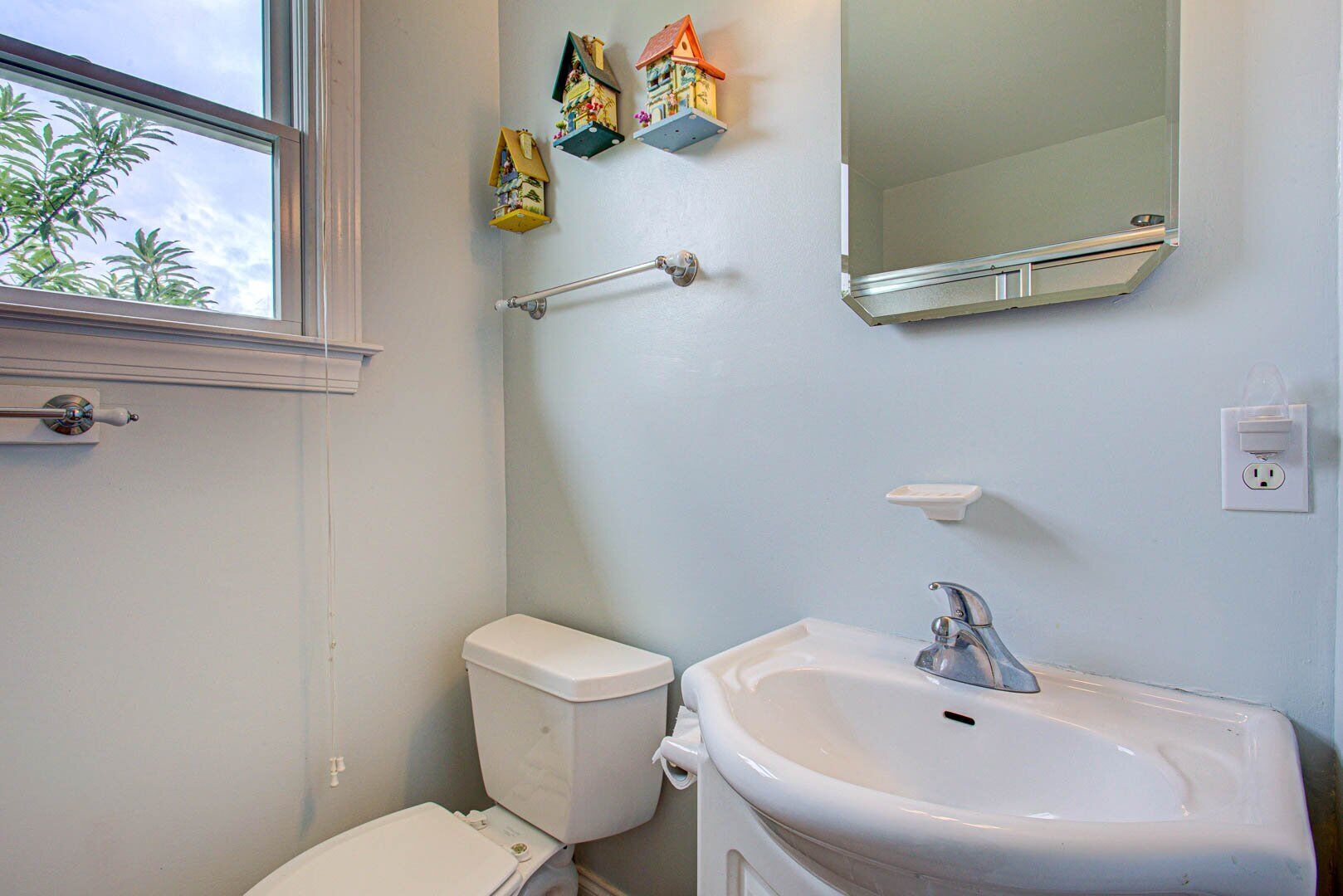 A bathroom with a toilet, sink, and window.