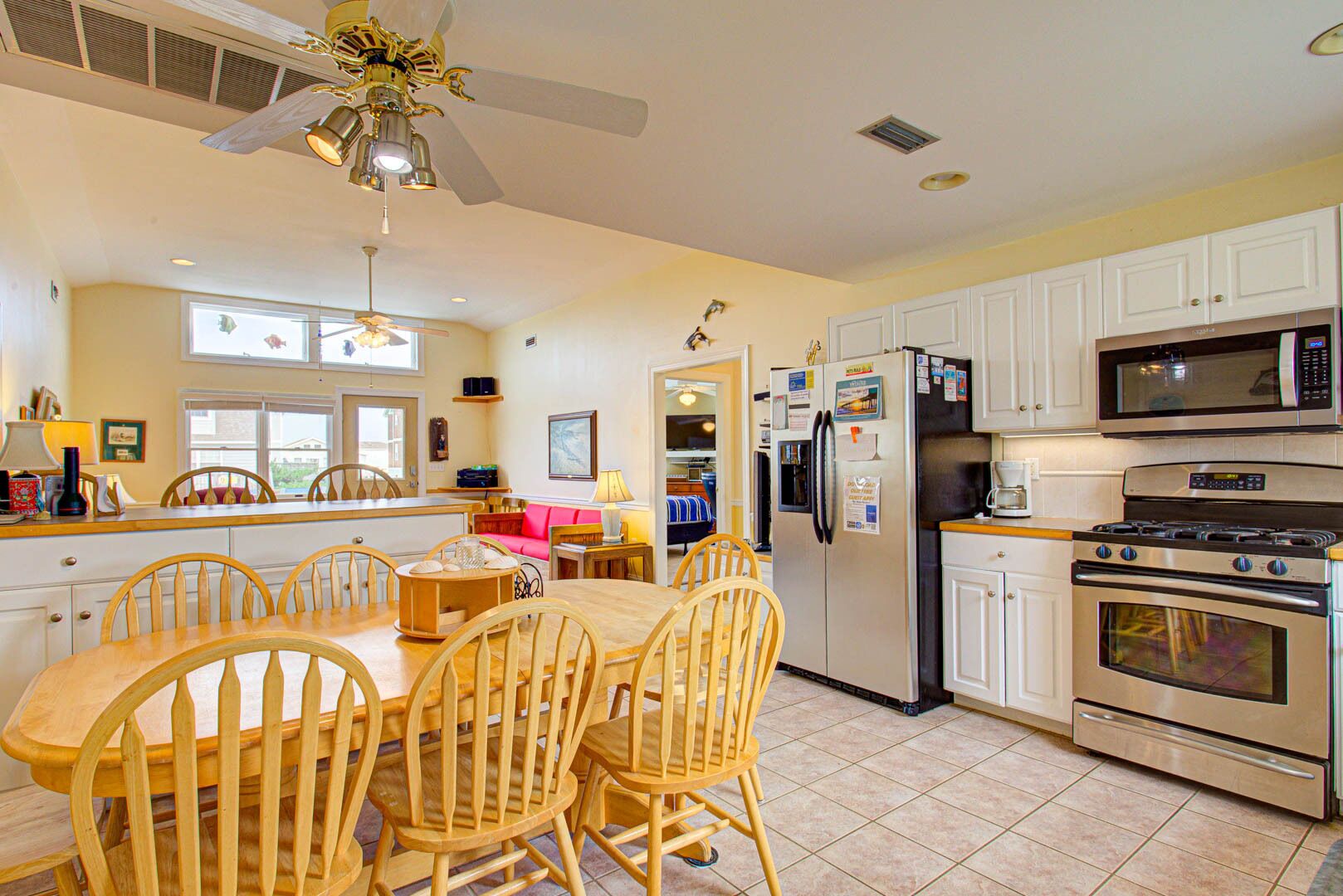 A spacious kitchen with white cabinets, a large island with chairs, a refrigerator, a microwave, and an oven.