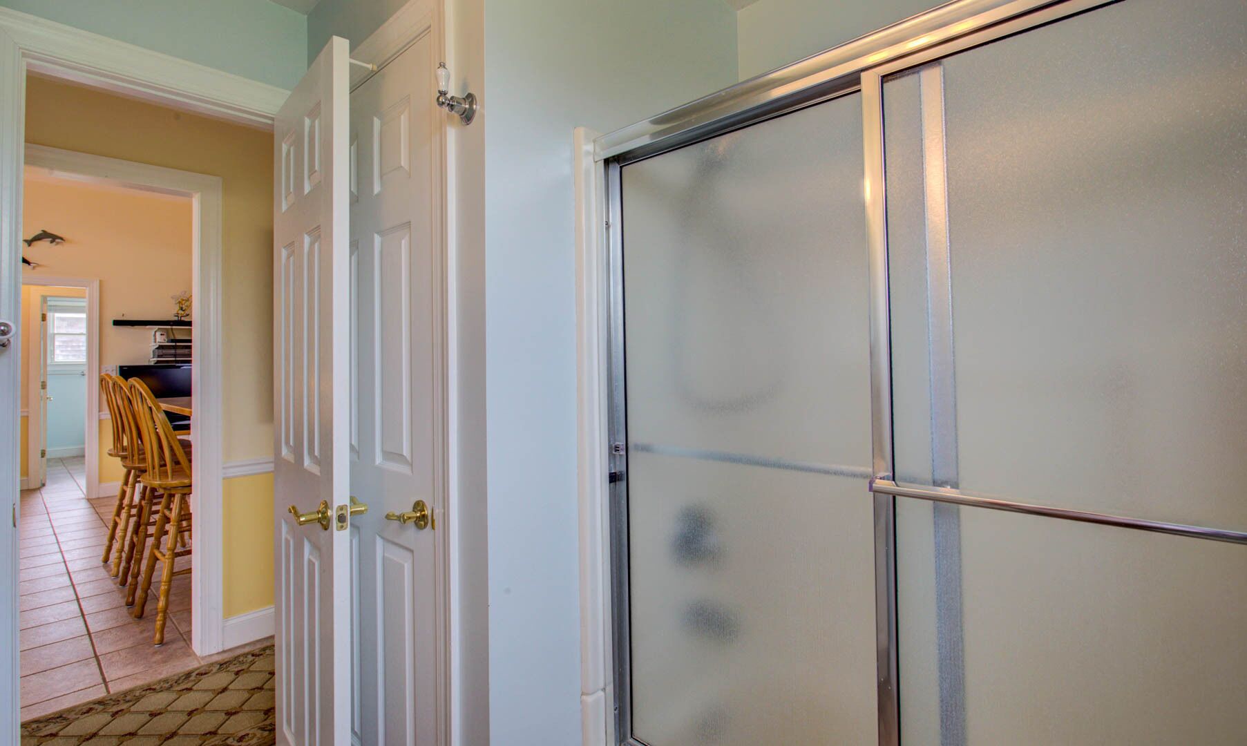 A room with a white door, a frosted glass window, and a tiled floor.
