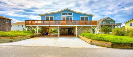 A two-story house with a covered driveway and a wooden deck.