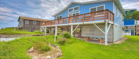 A two-story house with a wooden deck and a small garden area.