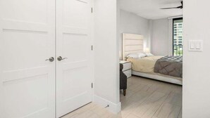 A bedroom with a bed, nightstand, and a white wardrobe. - Beachfront 2BR/2BA condo with heated pool, WiFi, and Marco Island views. (Marco Island)