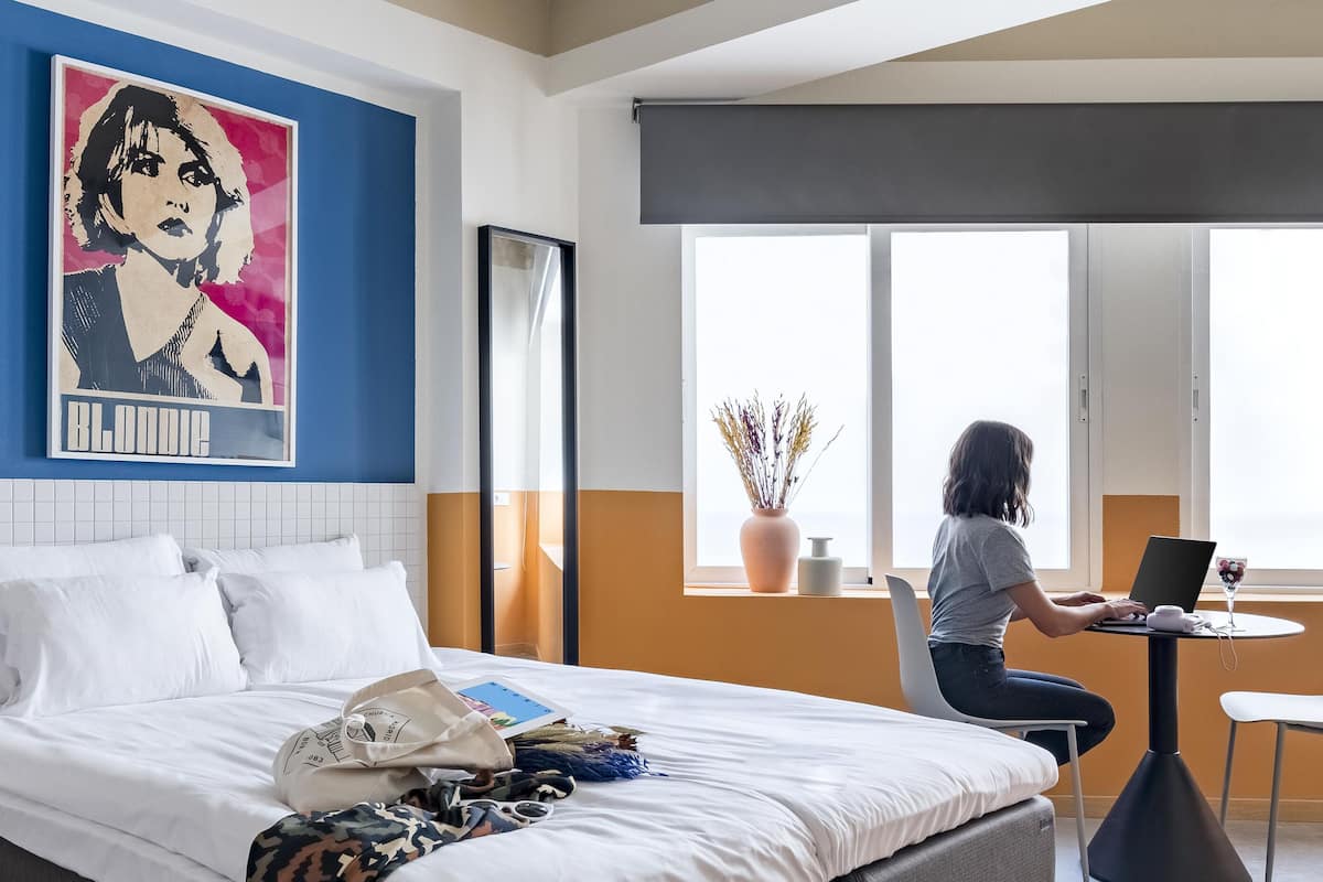 Una habitación de hotel con cama, escritorio y un ventanal grande.