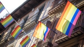Un edificio con varios balcones y una hilera de banderas arcoíris.
