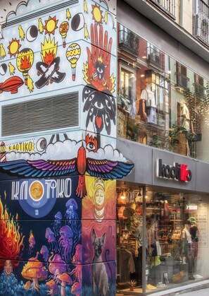Fachada de edificio con murales coloridos, una tienda visible llamada 'Kodiko' y una vista despejada de la calle.