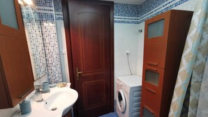 Ein kleines Badezimmer mit Waschbecken, Spiegel und Waschmaschine.
