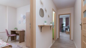 Un dormitorio moderno con un escritorio de madera, una silla, una cama y un pasillo que lleva a un baño.