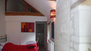A bedroom with a bed, a red blanket, a wall-mounted light fixture, and a painting. - RENAISSANCE cottage (Courchamps)