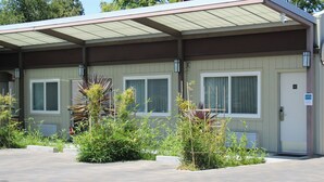 Ein Motel mit zwei Fenstern, einem überdachten Parkbereich und einer Tür, auf der die Nummer 201 angebracht ist.