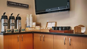 A coffee and tea station with labeled dispensers, a menu board, and a television mounted above the counter. - The Zen Hotel (Palo Alto)