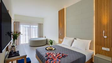 A modern hotel room with a large bed, a flat-screen TV, a desk, and a seating area.