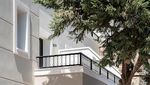 A modern building with a balcony, arched windows, and surrounding greenery. - Elia Platanias (Platanias)