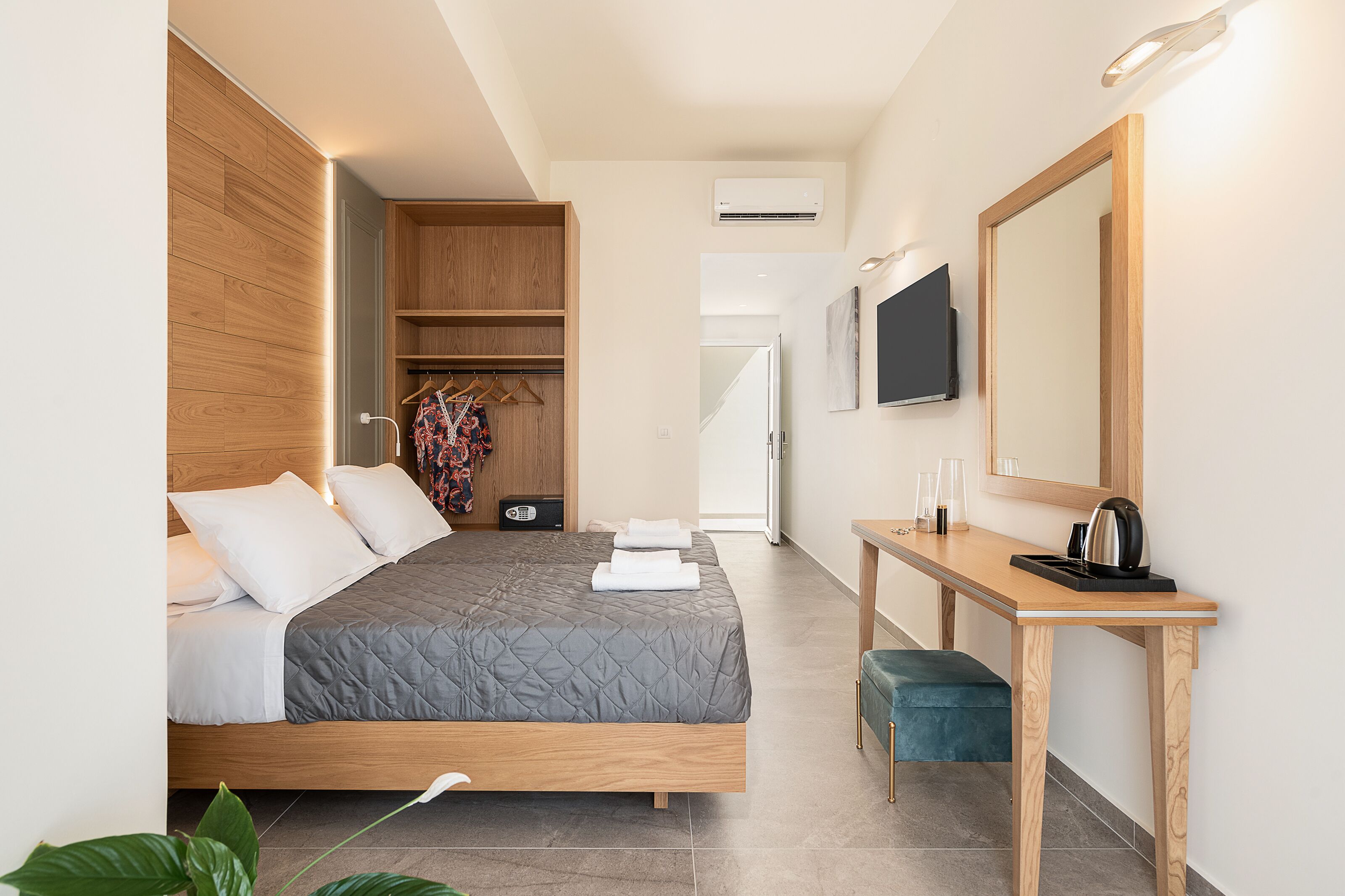 A modern hotel room with a wooden bed, a desk with a mirror, and a TV.
