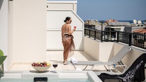A balcony with a hot tub, lounge chairs, and a bowl of fruit and wine. - Elia Platanias (Platanias)