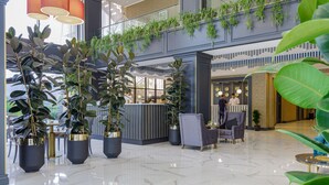 A modern lobby with marble flooring, potted plants, seating areas, and a reception desk. - Premium Park Hotel (Baku)