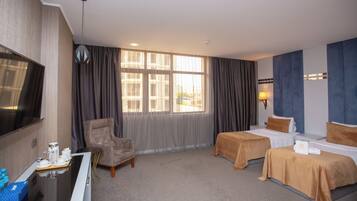 A hotel room with two beds, a desk with a chair, a TV, and a window with curtains.